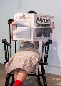 a woman sitting in a rocking chair reading a magazine
